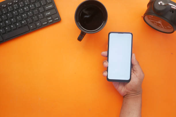 istock hand holding smart phone with empty screen on orange background 1327563230