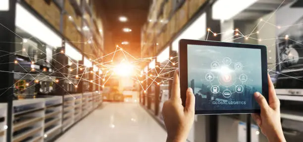 Hands hold tablet with global logistics network app at distribution warehouse. Intelligent innovation technology in shipping, import export transportation provide smart delivery to worldwide customer.