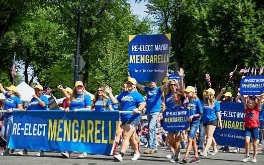 Prescott, Arizona, USA - July 3, 2021: People marching in the 4th of July parade holding re-elect mayor Mengarelli banners.