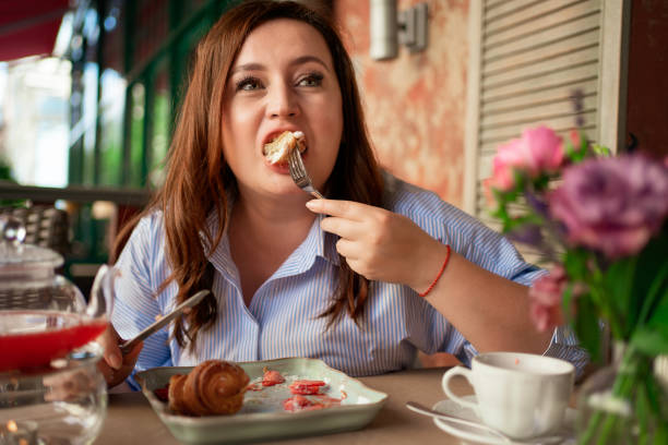 A woman eats a croissant with strawberries, mint and jam with a knife and fork. A woman eats a croissant with strawberries, mint and jam with a knife and fork. beautiful desserts in cafes. overweight because of the love of flour and sweets. kitchen knife photos stock pictures, royalty-free photos & images