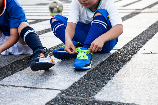 Preparation before starting sports.\nPractice tying shoelaces yourself.\nElementary school soccer player.