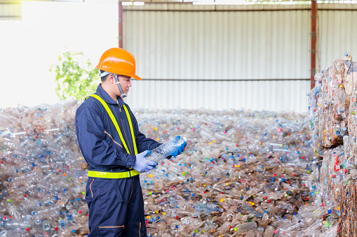 Employees in a recycling industry inspect plastic bottle raw materials to be used in the recycling process.