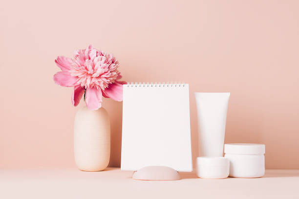 istock Womens accessories cream oil various cosmetics clean blank notebook on a table with flowers. Beauty concept 1327572184