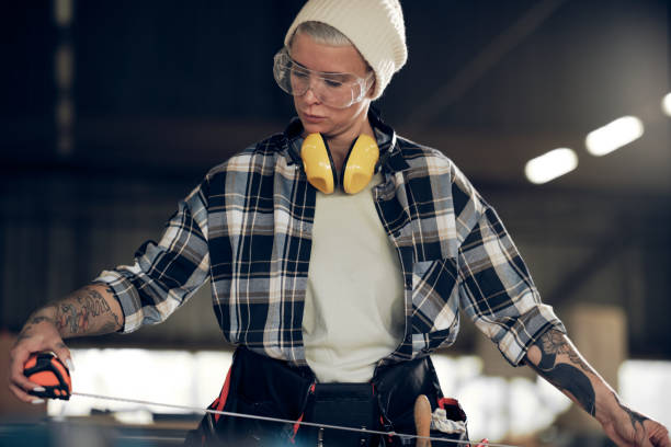 istock Female carpenter measuring plank with tape 1327574833