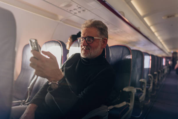 Senior man using phone on board the aircraft