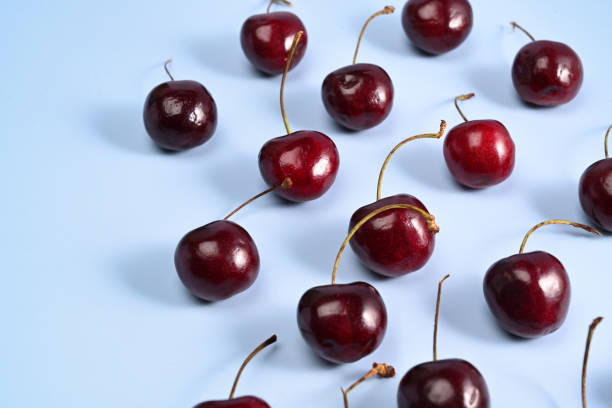 istock Ripe red cherries with leaves on blue background. 1327575554
