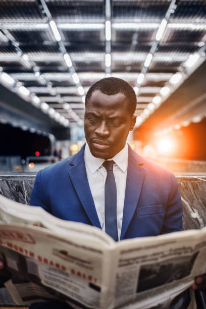 istock Businessman reading newspaper at subway station 1327575935