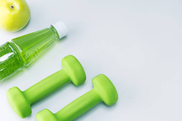 istock Dumbbells, fresh fruit apple and multivitamin juice on light grey surface with copy space. Healthy sport and diet concept. 1327578464