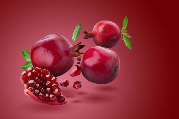 istock Ripe pomegranate fruit on red background. 1327578533