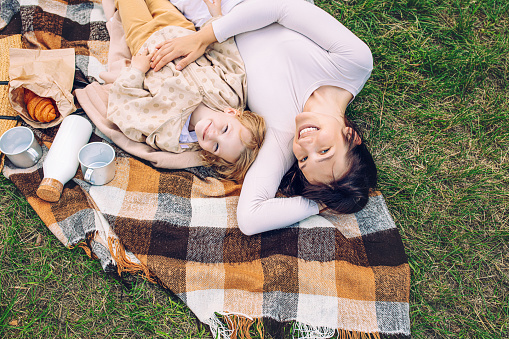 Family mother and daughter relax in nature on a blanket on the grass during a picnic