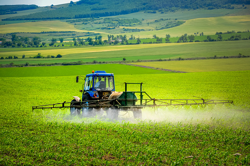 Farming tractor plowing and spraying on field