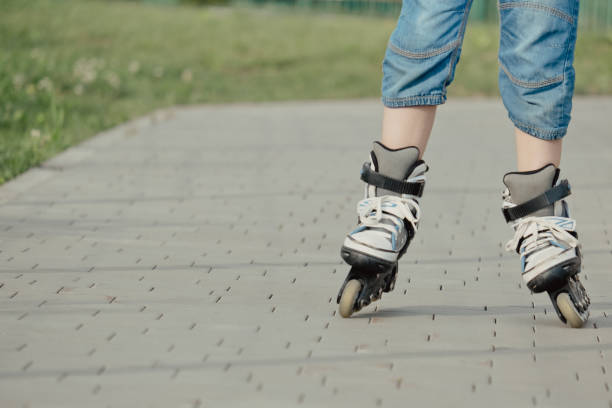 istock Little boy in protective equipment and rollers stands on walkway in park, low angle view 1327585335