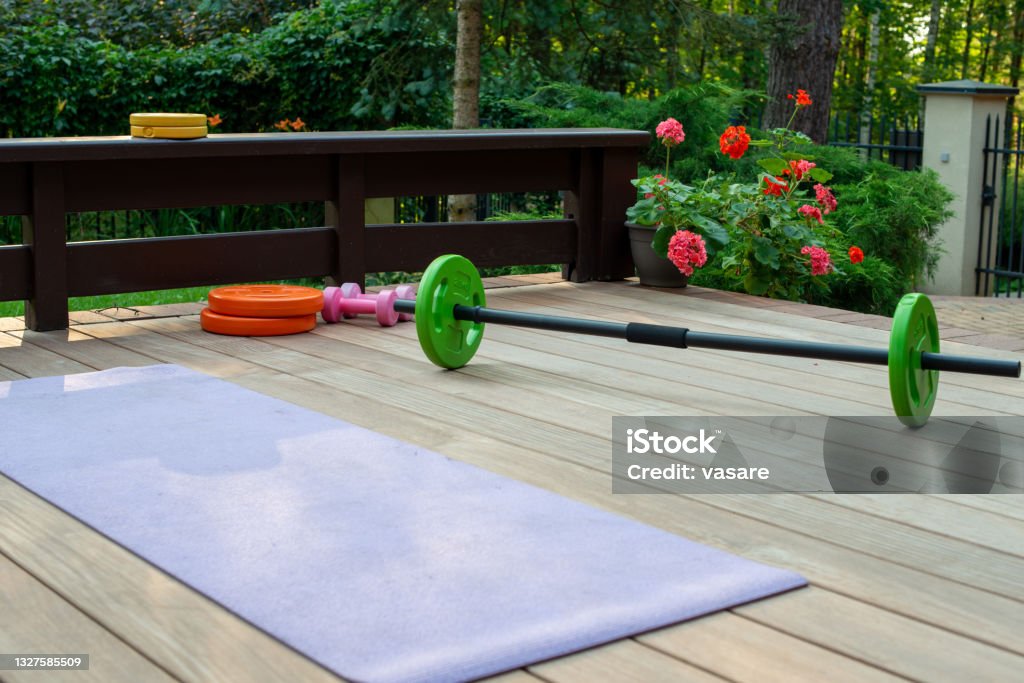 Home training equipment on home yard terrace - yoga mat and  weighs. Fitness at home. Home training equipment on home yard terrace - yoga mat and  weighs. Fitness at home. Healthy, training and lifestyle concept. Gym Stock Photo