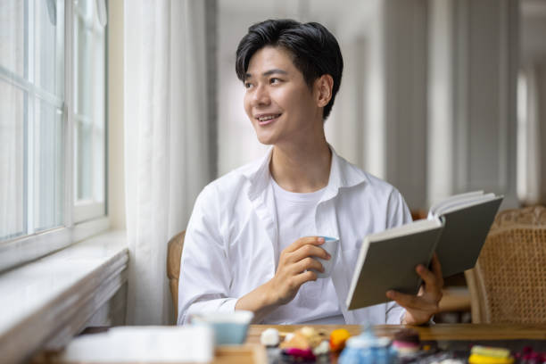 Asian man reading in a coffee shop stock photo