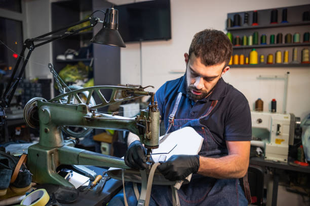 istock Young man stitching women's leather purse on special sewing machine 1327585833