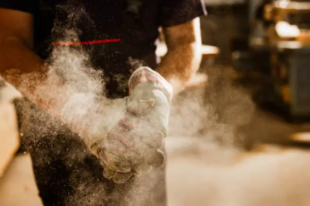 Photo of Close up of unrecognizable worker cleaning dust from his gloves.