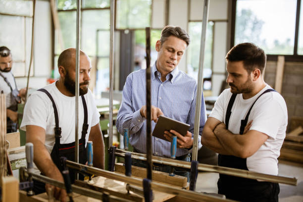 istock Young carpenters and their manager working on touchpad in a workshop. 1327586409