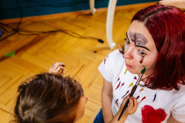 istock Family leisure activity home concept. Mother and small daughter drawing, fun using paintbrushes and watercolors. Children and parent creating picture together, watercolor on face, home quarantine. 1327586448