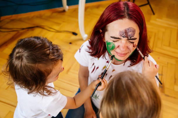 istock Family hobbies leisure activity home concept. Mother and small daughter drawing with fun using paintbrushes and watercolors. Children and parent creating picture together, body paint, home quarantine. 1327586548