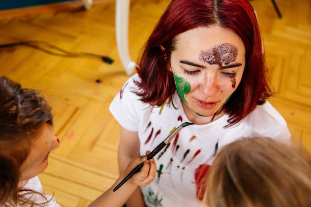 istock Family leisure activity home concept. Mother and small daughter drawing, fun using paintbrushes and watercolors. Children and parent creating picture together, watercolor on face, home quarantine. 1327586592