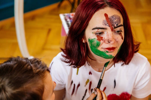 istock Family leisure activity home concept. Mother and small daughter drawing, fun using paintbrushes and watercolors. Children and parent creating picture together, watercolor on face, home quarantine. 1327586623