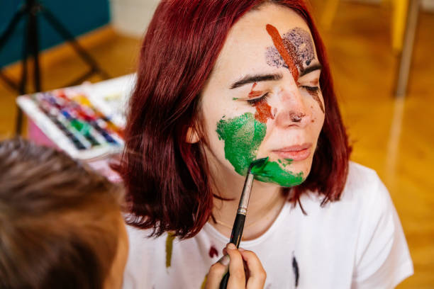 istock Family leisure activity home concept. Mother and small daughter drawing, fun using paintbrushes and watercolors. Children and parent creating picture together, watercolor on face, home quarantine. 1327586748