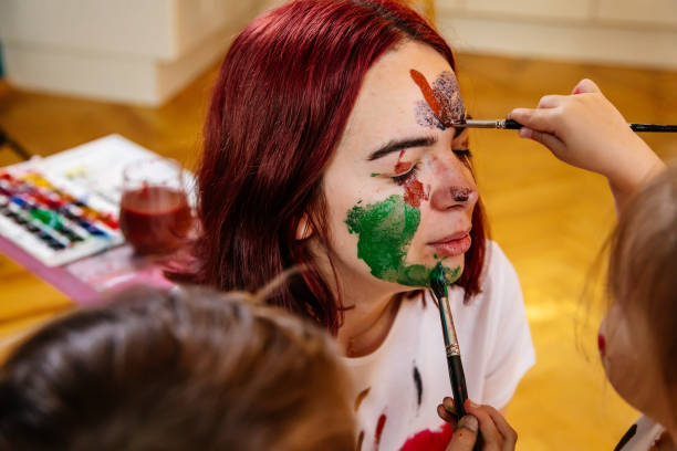 istock Family leisure activity home concept. Mother and small daughter drawing, fun using paintbrushes and watercolors. Children and parent creating picture together, watercolor on face, home quarantine. 1327586777