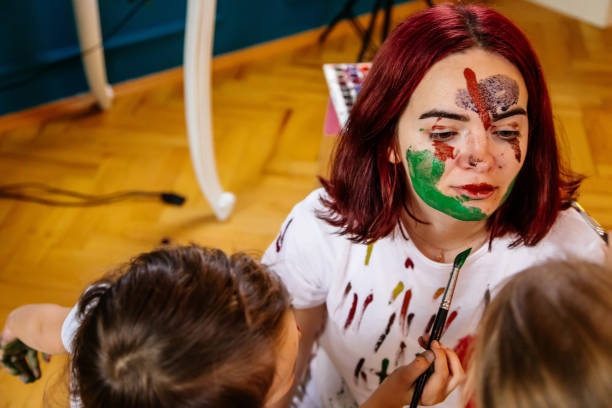 istock Family leisure activity home concept. Mother and small daughter drawing, fun using paintbrushes and watercolors. Children and parent creating picture together, watercolor on face, home quarantine. 1327586809