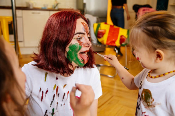 istock Family hobbies leisure activity home concept. Mother and small daughter drawing with fun using paintbrushes and watercolors. Children and parent creating picture together, body paint, home quarantine. 1327586820