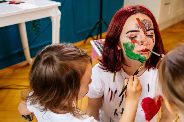 istock Family leisure activity home concept. Mother and small daughter drawing, fun using paintbrushes and watercolors. Children and parent creating picture together, watercolor on face, home quarantine. 1327586898