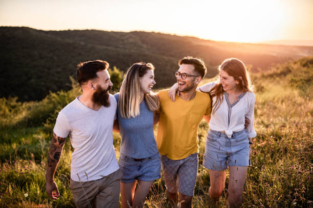 istock Happy embraced friends talking and walking on a hill at sunset. 1327587602