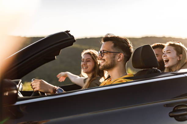 istock Group of happy friends having fun while going on a trip in a convertible car. 1327587624