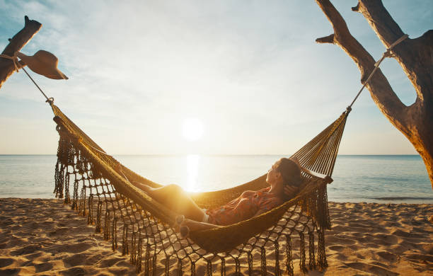 Vacation Beach Summer Holiday Concept. Young woman relaxing in hammock at sunset, island Phu Quoc, Vietnam stock photo