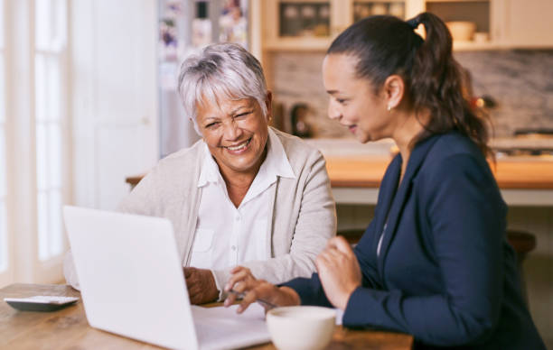 foto de una mujer de la tercera edad usando una computadora portátil durante una reunión con un consultor en casa - portfolio investment will tax fotografías e imágenes de stock