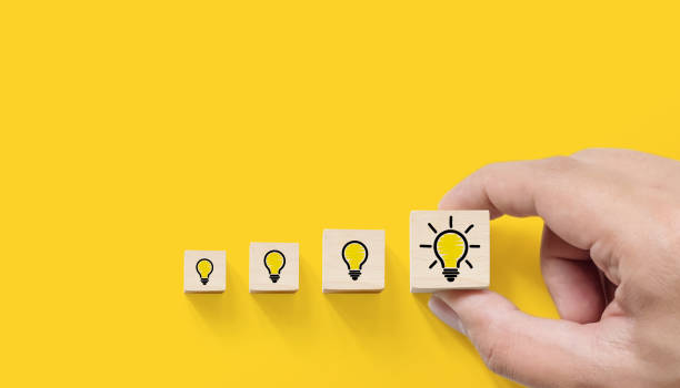 istock Concept creative idea and innovation. Hand picked wooden cube block with light bulb icon on yellow background 1327589734