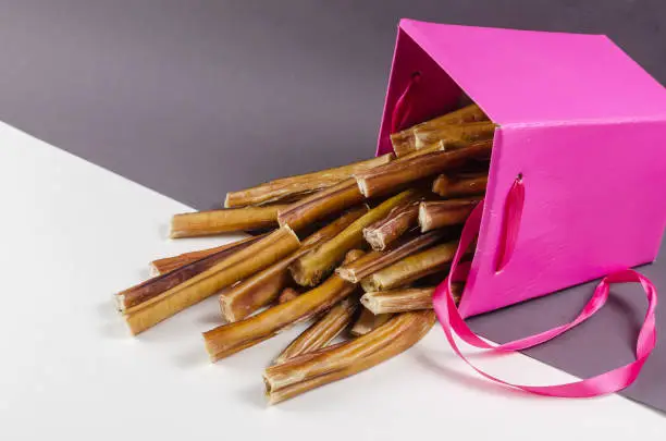Photo of Beautiful pink gift box with pet treats. Bully sticks for dogs o