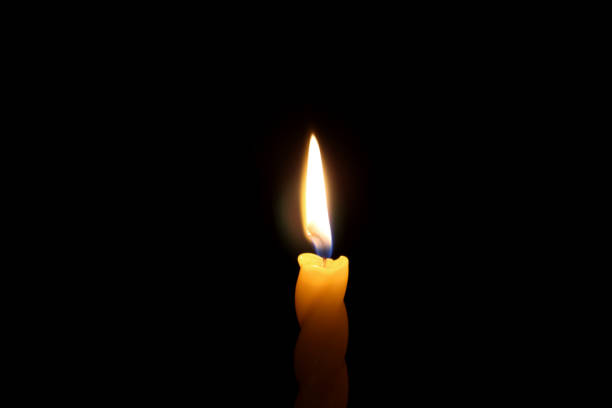 istock Flame of a single candle on a dark background. 1327594142