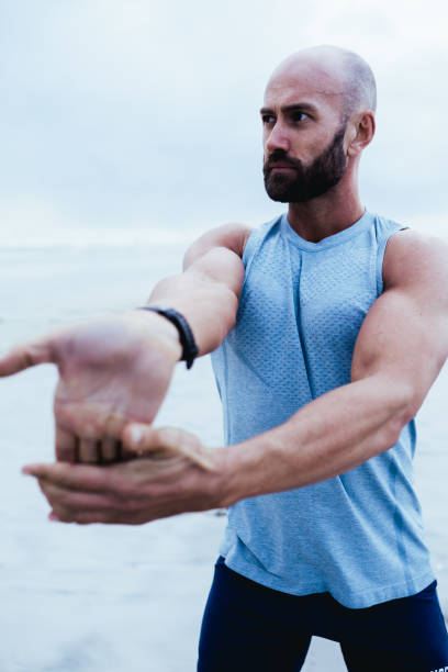 istock Fitness model stretching palms on beach 1327596138