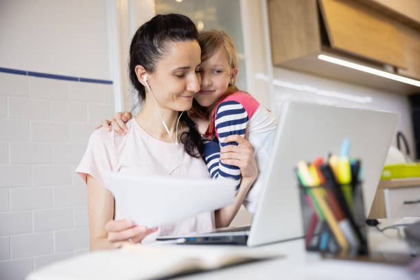 istock Mother working from home using laptop, cuddling with her daughter seeking attention 1327596463