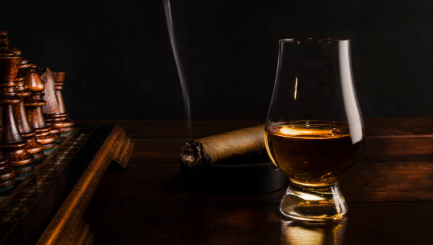 Whiskey, Smoking Cigar and Chess Smoking cigar in a dark room near whisky in a glass and wooden chess board on a wooden table. chess board photos stock pictures, royalty-free photos & images
