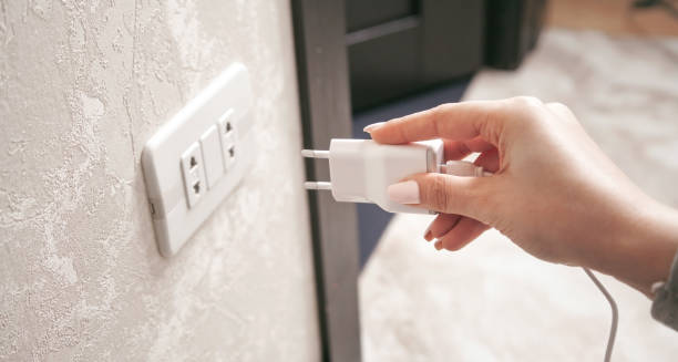istock Female hand plugs the phone charger into the socket. 1327597832