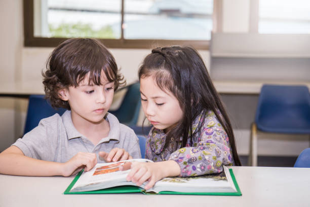 Two young children reading books at the school library, Education concept Two young children reading books at the school library, Education concept literacy photos stock pictures, royalty-free photos & images