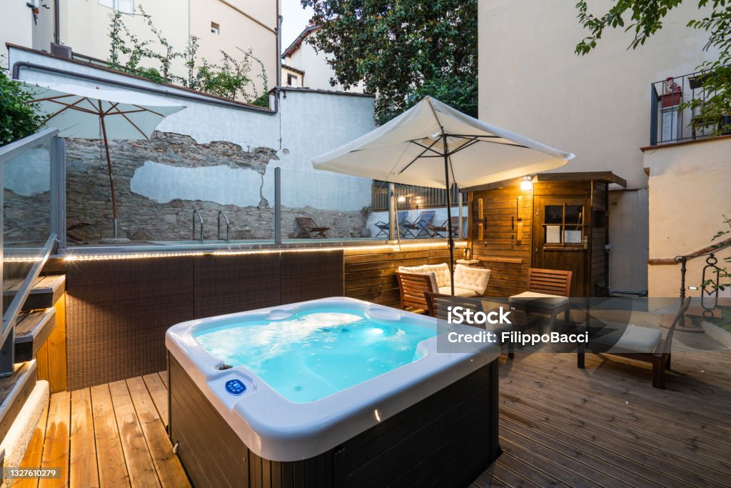 Tourist resort with a hot tub and a swimming pool during sunset Tourist resort with a hot tub and a swimming pool during sunset. Luxury hotel with deckchairs. Hot Tub Stock Photo