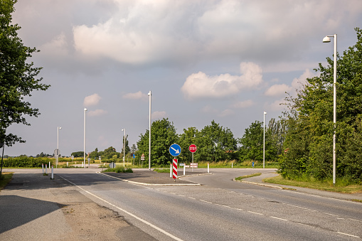 Traffic signs and street lamps at a road intersection at the countryside at the Danish island Lolland