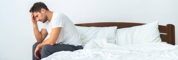 istock The unhappy man sitting on the bed on the white background 1327612346