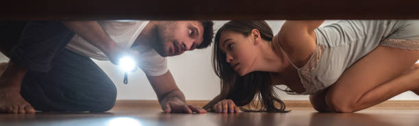 istock The man and a woman with a flashlight looking under the bed 1327612367
