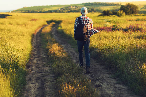 istock Active tourist, a man with a briefcase in nature, a hipster in a cap is walking along a path on a green hill, healthy lifestyle 1327612380