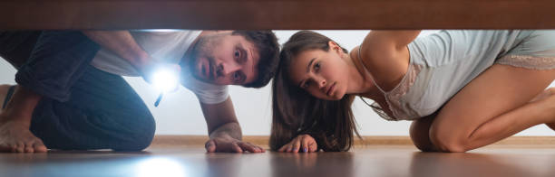 istock The man and a woman with a flashlight looking under the bed 1327612448