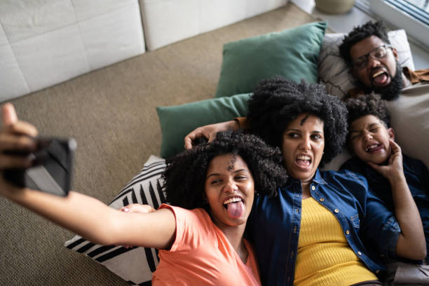 famille ensemble gisant sur le sol en prenant des selfies à la maison - grimacing male african descent teenage boys photos et images de collection