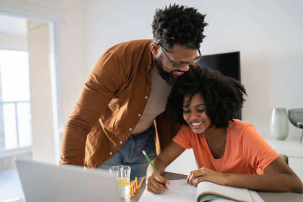 father helping daughter with homework - parents imagens e fotografias de stock